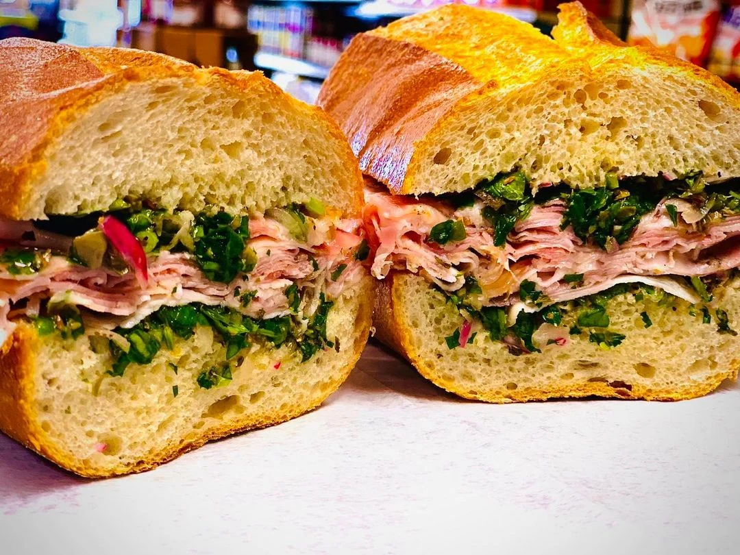 Two halves of Pastore’s Porchetta Verde sandwich with roast pork and greens